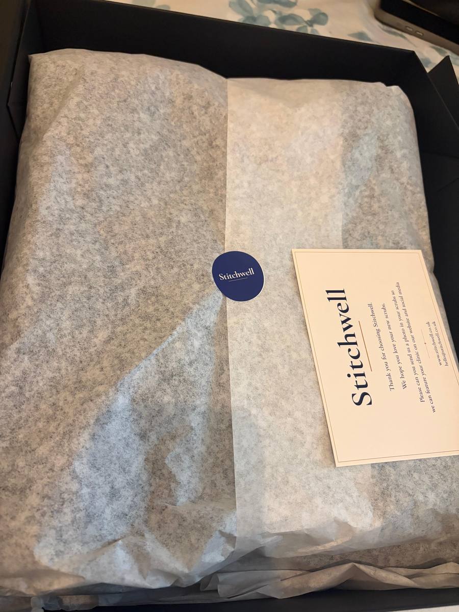 A personalised uniform order wrapped in tissue paper inside a Stitchwell gift box